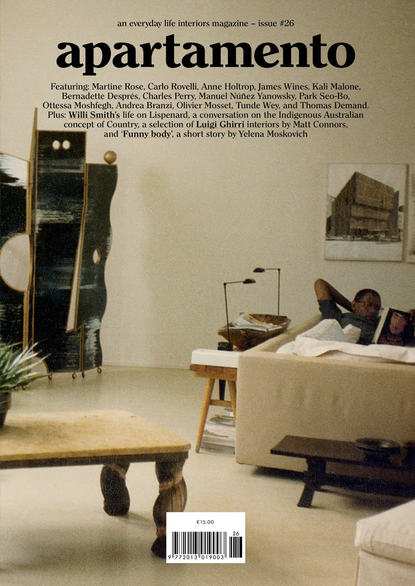Apartamento magazine issue 26 cover, person reading on a beige sofa in a living room with a folding screen and artwork